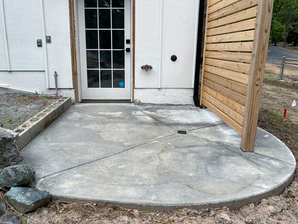 Finished outdoor shower slab sloped toward drain with curved relief cuts